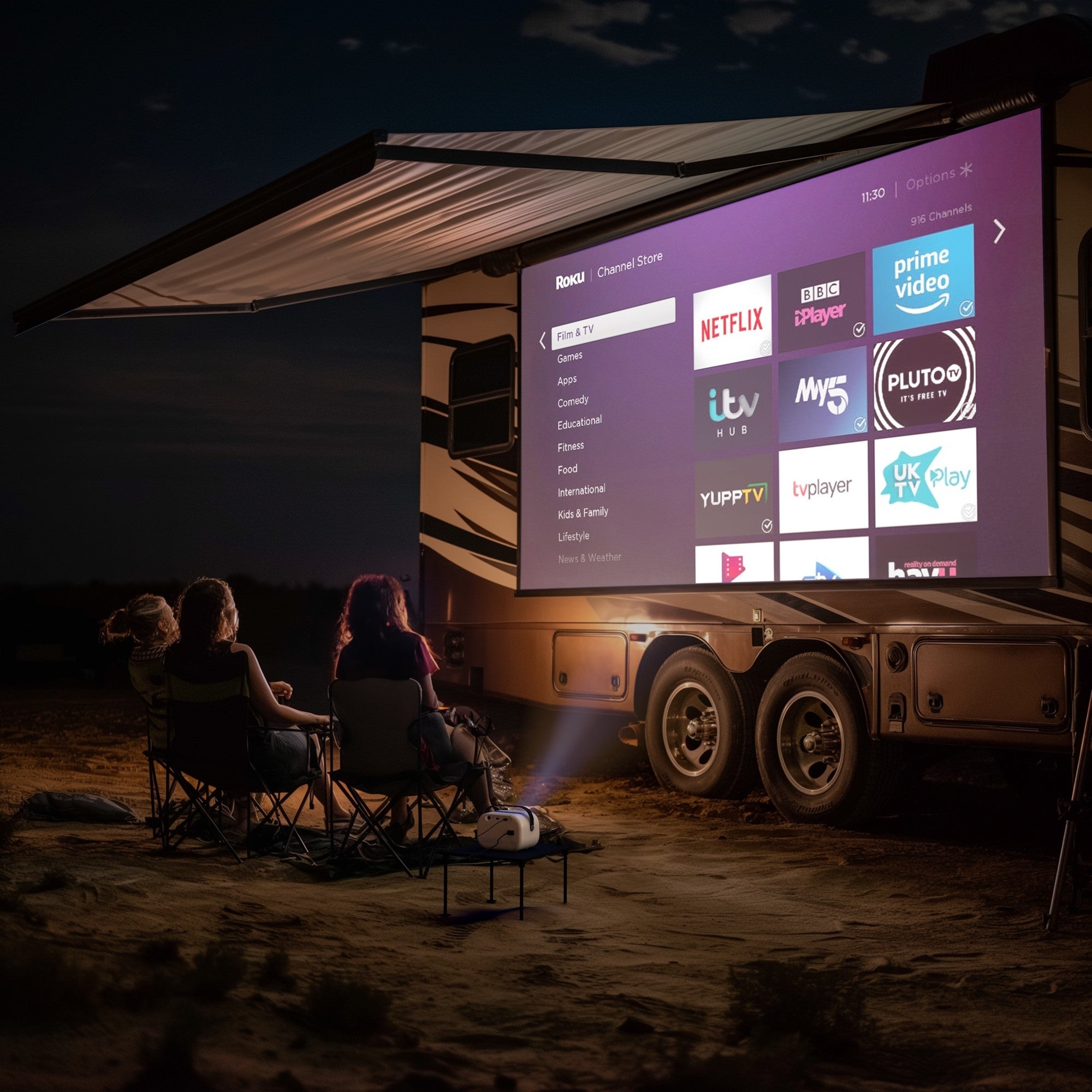 Three people sitting outdoors in the evening, watching a movie projected onto the side of an RV using the Lumi projector. The projector displays a Roku streaming menu with popular streaming apps like Netflix, Prime Video, and BBC iPlayer. The projector is set up on a small stand, and the scene takes place in a quiet, dark landscape under an awning, creating a cozy, outdoor movie experience.