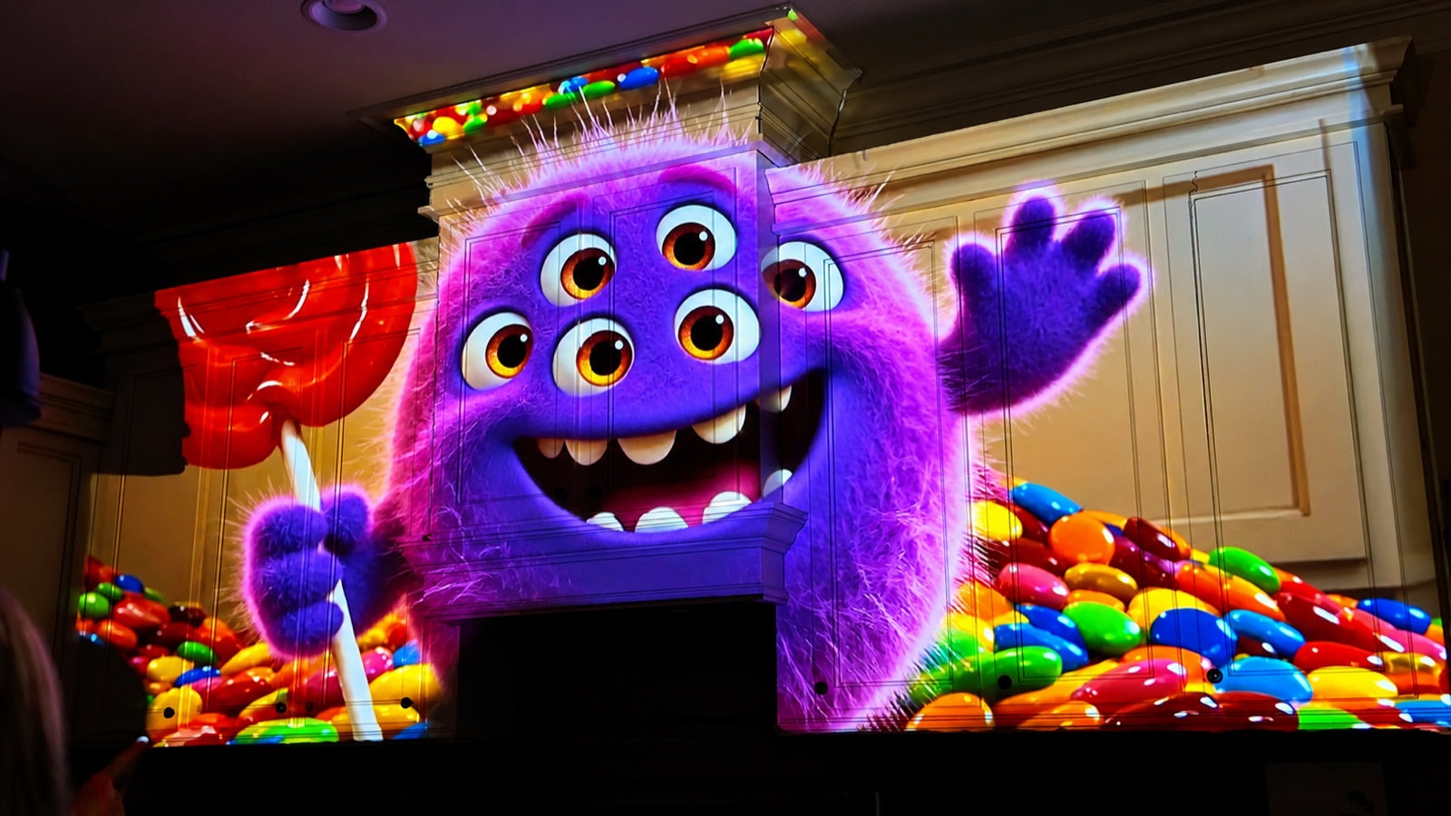 Friendly purple monster and candy projection mapped across kitchen cabinets